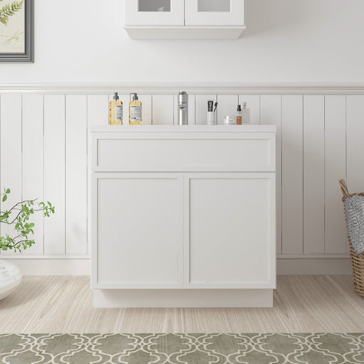 White 33-inch bathroom vanity base cabinet with two closed shaker doors and drawer, front-facing room setting with white sink