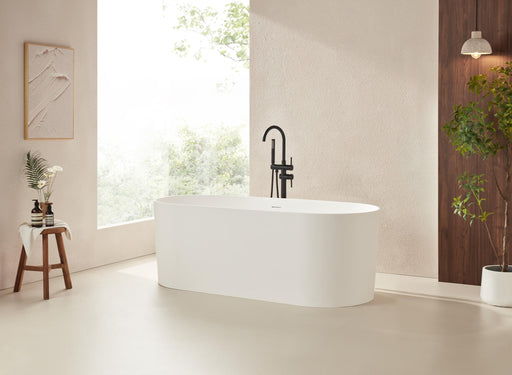 White freestanding stone resin bathtub with round matte black faucet in bright beige bathroom setting