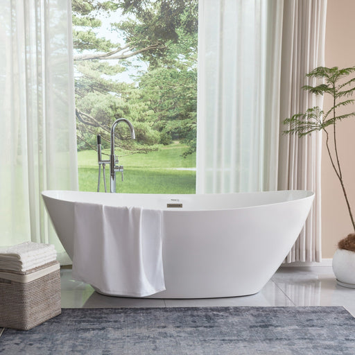 White oval freestanding bathtub with draped white towel over rim beside large window with lush outdoor view